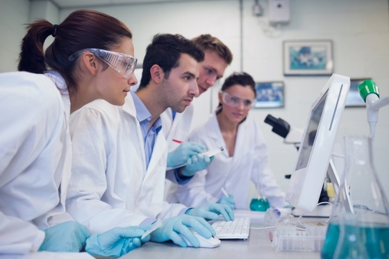 Group of four researchers in a lab environment all looking at a screen together