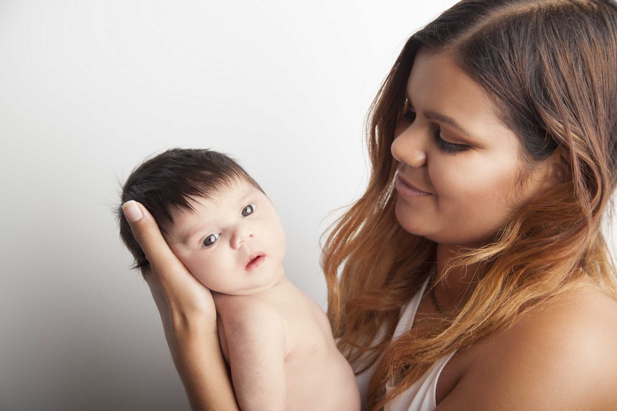 A young First Nations mother holds her new born baby and looks at them lovingly